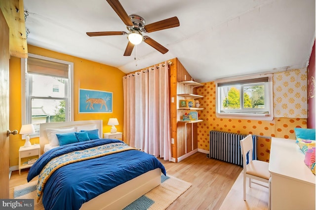 bedroom with wallpapered walls, baseboards, lofted ceiling, radiator heating unit, and wood finished floors