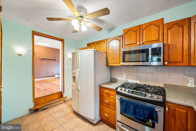 kitchen featuring stainless steel appliances, brown cabinets, decorative backsplash, and light tile patterned floors