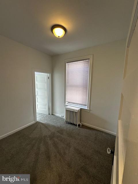 spare room with baseboards, carpet, and radiator