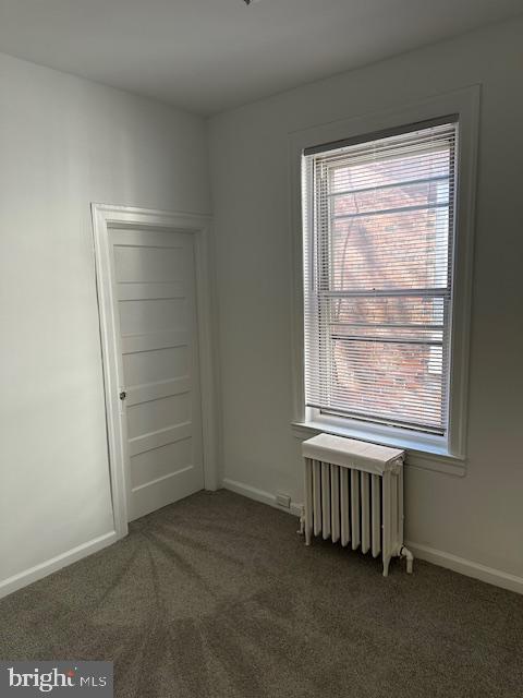 empty room with baseboards, a healthy amount of sunlight, carpet flooring, and radiator