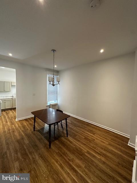 unfurnished dining area featuring recessed lighting, dark wood-style flooring, a notable chandelier, and baseboards