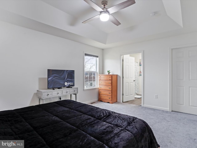 carpeted bedroom featuring baseboards, a raised ceiling, a ceiling fan, and ensuite bathroom