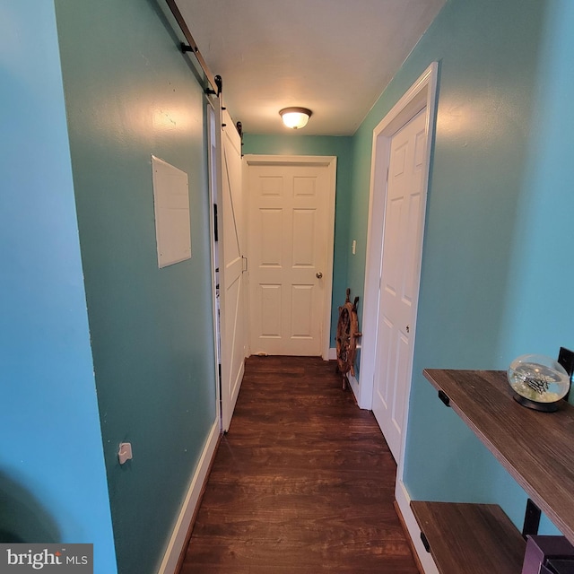 corridor featuring dark wood-style floors, a barn door, and baseboards