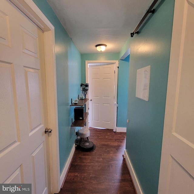 corridor featuring dark wood-type flooring and baseboards