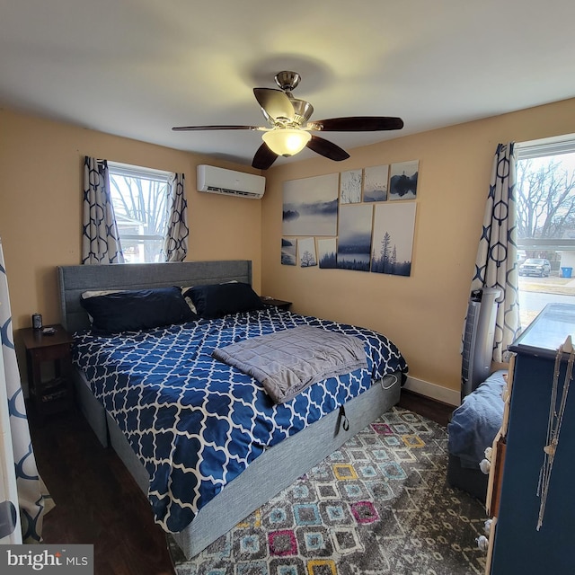 bedroom featuring ceiling fan, a wall mounted air conditioner, wood finished floors, and baseboards