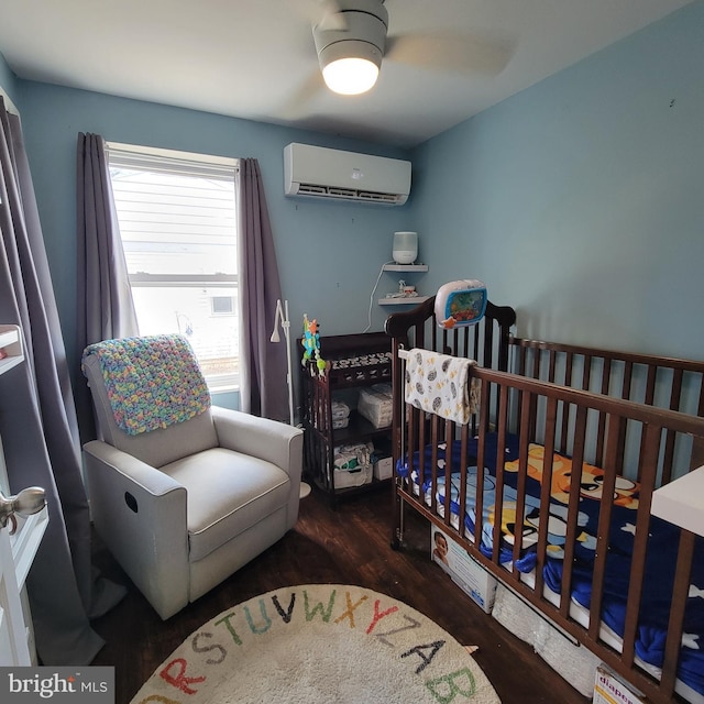 bedroom featuring a crib, a wall mounted AC, and wood finished floors