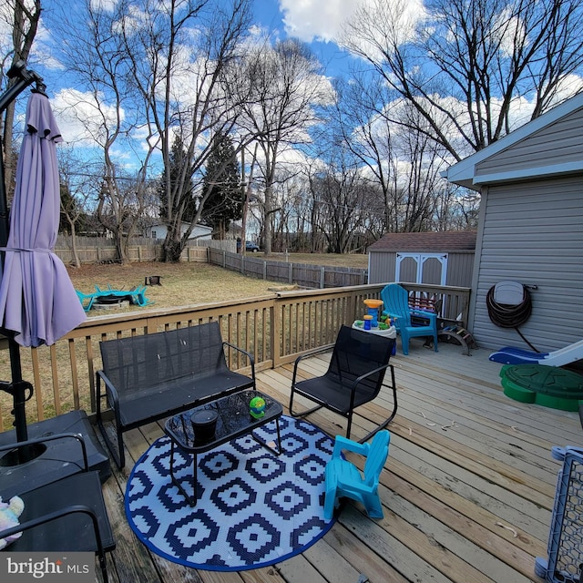 wooden terrace with an outbuilding, a fenced backyard, a storage shed, outdoor lounge area, and a yard