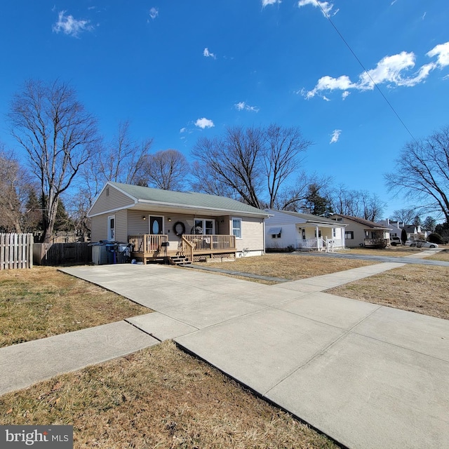 ranch-style house with covered porch, driveway, a front lawn, and fence