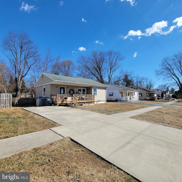 ranch-style house featuring covered porch, fence, concrete driveway, and a front yard