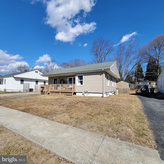 view of front of home with driveway, a deck, and a front yard