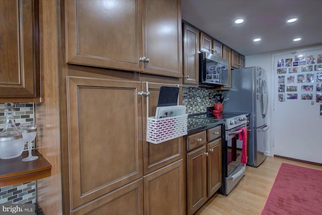 kitchen featuring baseboards, light wood-style flooring, recessed lighting, stainless steel appliances, and tasteful backsplash