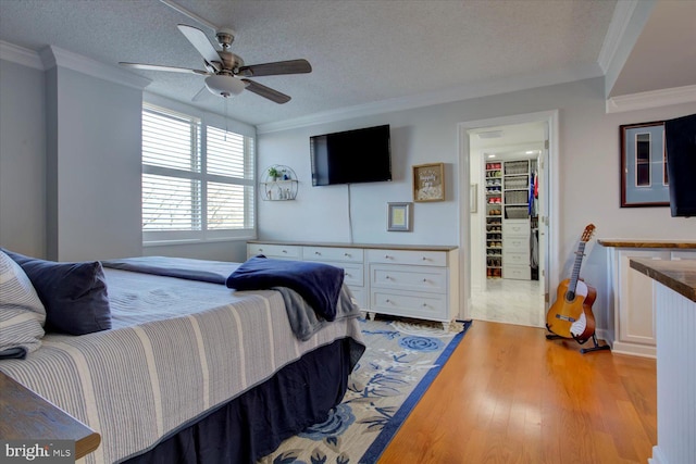 bedroom featuring crown molding, a spacious closet, and light wood-style floors