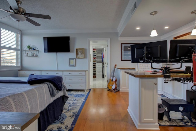 bedroom featuring visible vents, wood finished floors, a textured ceiling, and ornamental molding