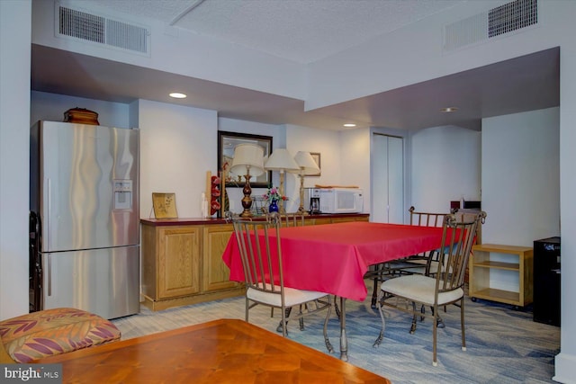 dining room with recessed lighting, visible vents, light wood-type flooring, and a textured ceiling