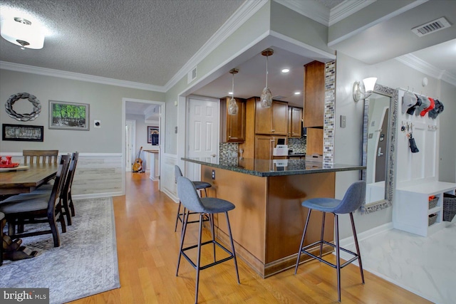 kitchen with visible vents, brown cabinets, a breakfast bar area, and light wood-style flooring