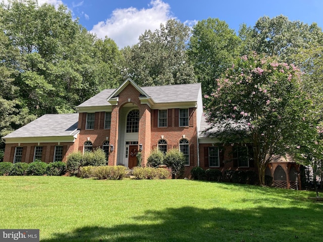 view of front of home with a gazebo, a front yard, and brick siding