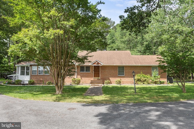 ranch-style house featuring brick siding, a front lawn, and a shingled roof