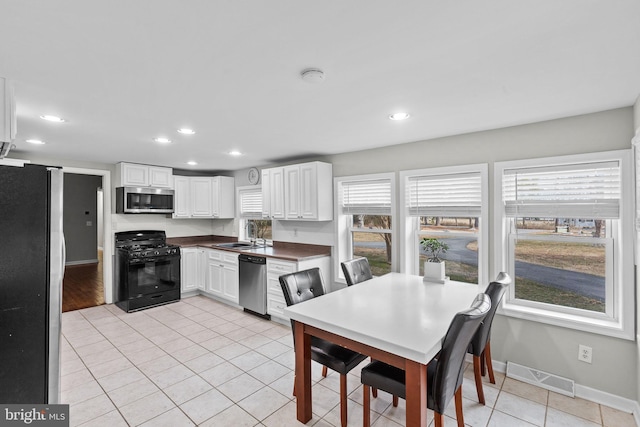 kitchen with visible vents, a sink, dark countertops, stainless steel appliances, and light tile patterned floors