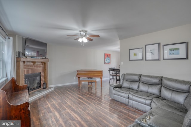 living area with a fireplace, wood finished floors, a ceiling fan, and baseboards