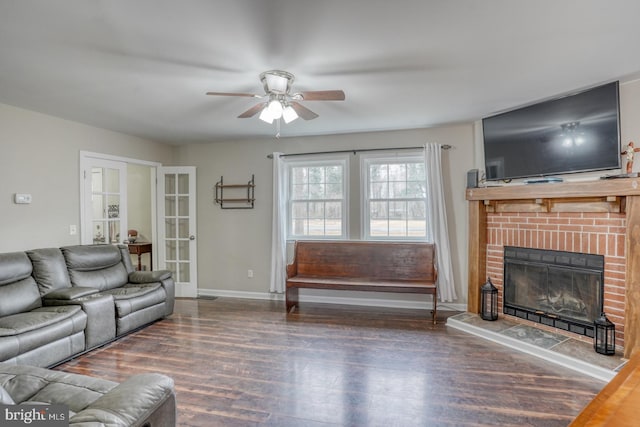 living room featuring baseboards, ceiling fan, wood finished floors, french doors, and a brick fireplace