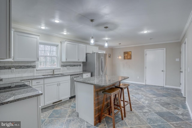 kitchen featuring light stone counters, tasteful backsplash, appliances with stainless steel finishes, a kitchen island, and a sink