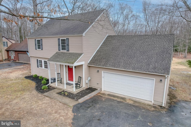 traditional home featuring a shingled roof, driveway, and an attached garage