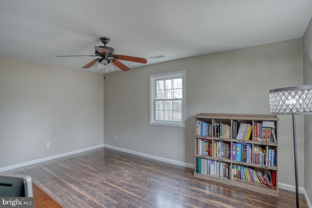 spare room featuring baseboards, visible vents, ceiling fan, and wood finished floors