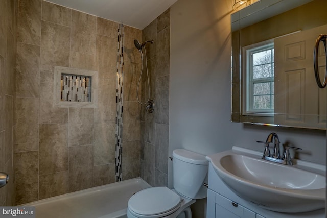 bathroom featuring toilet, a tile shower, and vanity