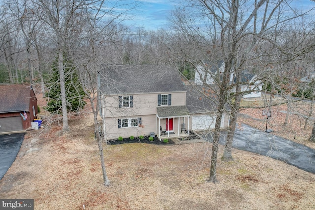 view of front of property featuring aphalt driveway, roof with shingles, and a front yard