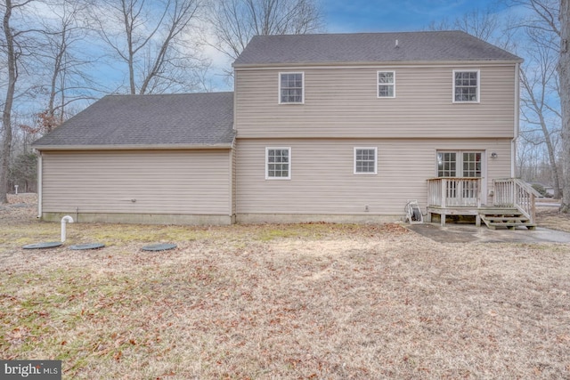 back of property with a shingled roof and a deck