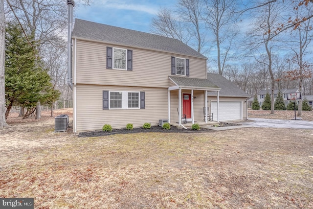 colonial inspired home featuring an attached garage, cooling unit, driveway, roof with shingles, and a front yard