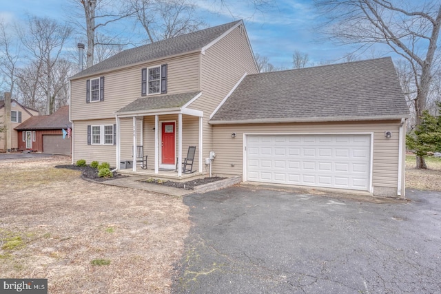 colonial home with a garage, roof with shingles, and driveway