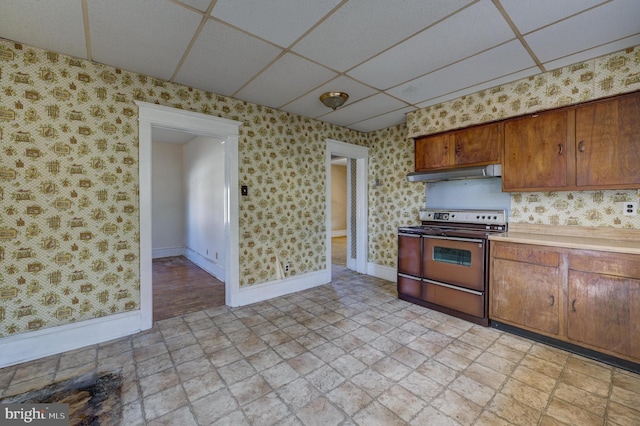 kitchen featuring a paneled ceiling, electric stove, under cabinet range hood, and wallpapered walls