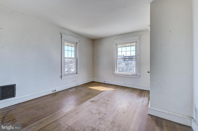 unfurnished room with hardwood / wood-style flooring and visible vents