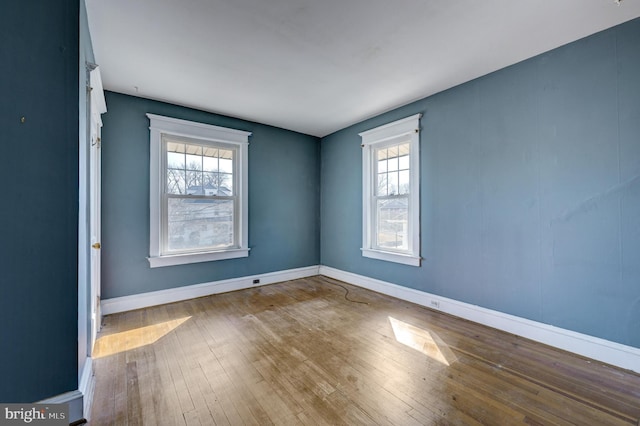 empty room featuring baseboards, a healthy amount of sunlight, and hardwood / wood-style floors