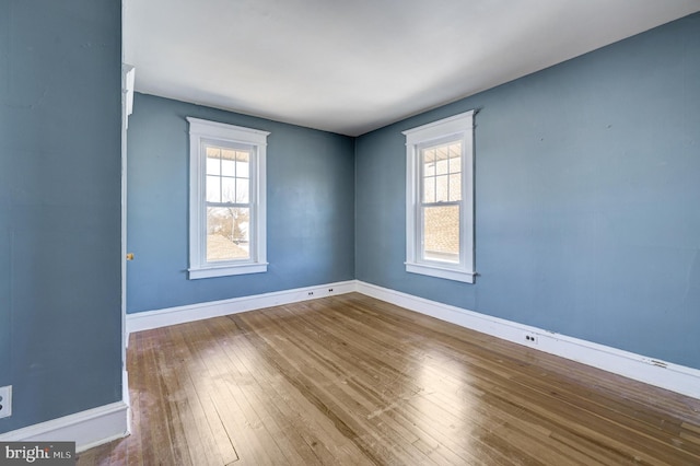 spare room featuring wood-type flooring and baseboards