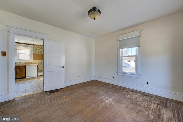 unfurnished room featuring visible vents, hardwood / wood-style flooring, and baseboards