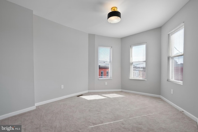 empty room featuring carpet floors, visible vents, and baseboards