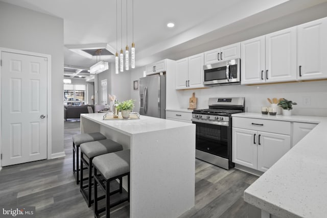 kitchen featuring stainless steel appliances, dark wood-type flooring, a breakfast bar area, and a center island