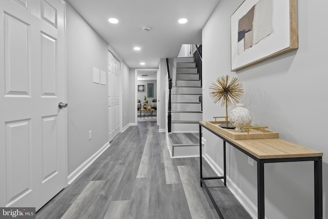 corridor featuring stairs, baseboards, wood finished floors, and recessed lighting