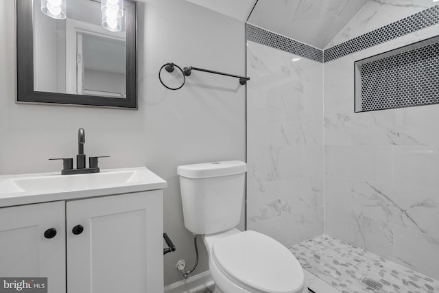 bathroom featuring lofted ceiling, a tile shower, vanity, and toilet