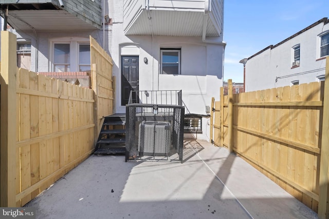 rear view of property with central AC, fence, and stucco siding