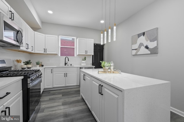 kitchen with tasteful backsplash, white cabinets, appliances with stainless steel finishes, a center island, and a sink