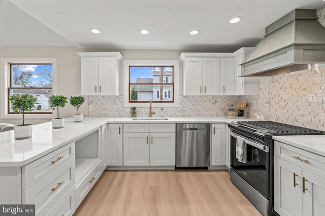 kitchen with range with gas cooktop, custom range hood, stainless steel dishwasher, white cabinetry, and a sink