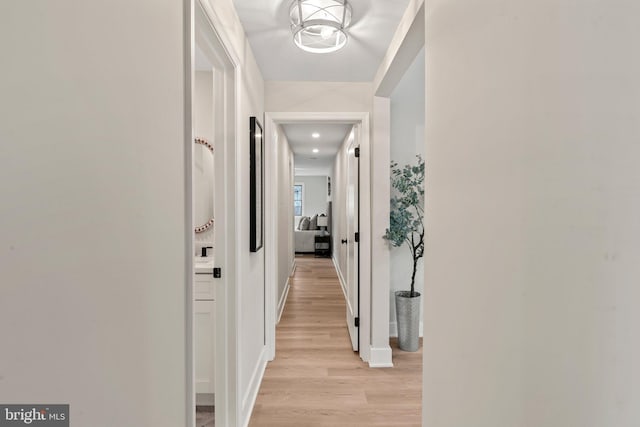 hall with light wood-style flooring and baseboards