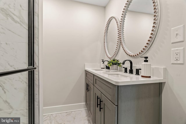 bathroom with a sink, baseboards, marble finish floor, and double vanity