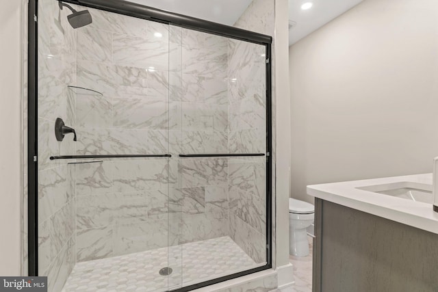 bathroom featuring marble finish floor, a stall shower, toilet, and vanity