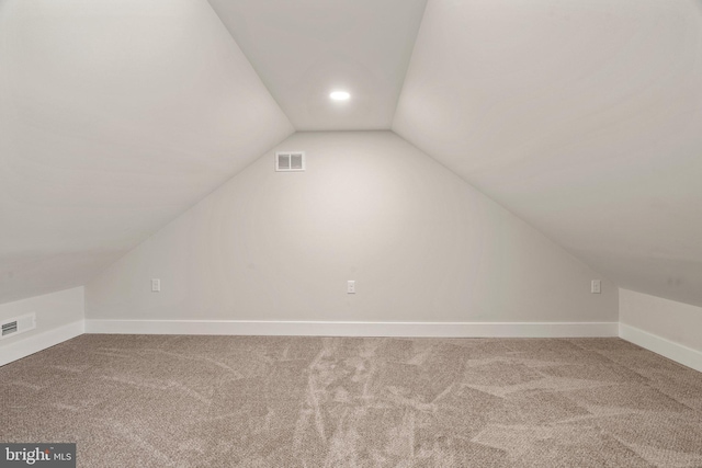 additional living space featuring visible vents, lofted ceiling, and carpet floors