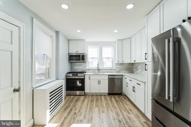 kitchen featuring a sink, white cabinetry, light countertops, appliances with stainless steel finishes, and decorative backsplash