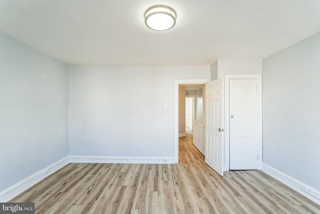 empty room featuring light wood finished floors and baseboards